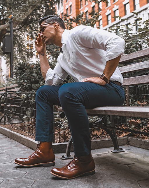 Image of social media influencer Mark from the duo "The NYC Couple" wearing the Madison Cap Toe Lace Boot in Cognac on a park bench.
